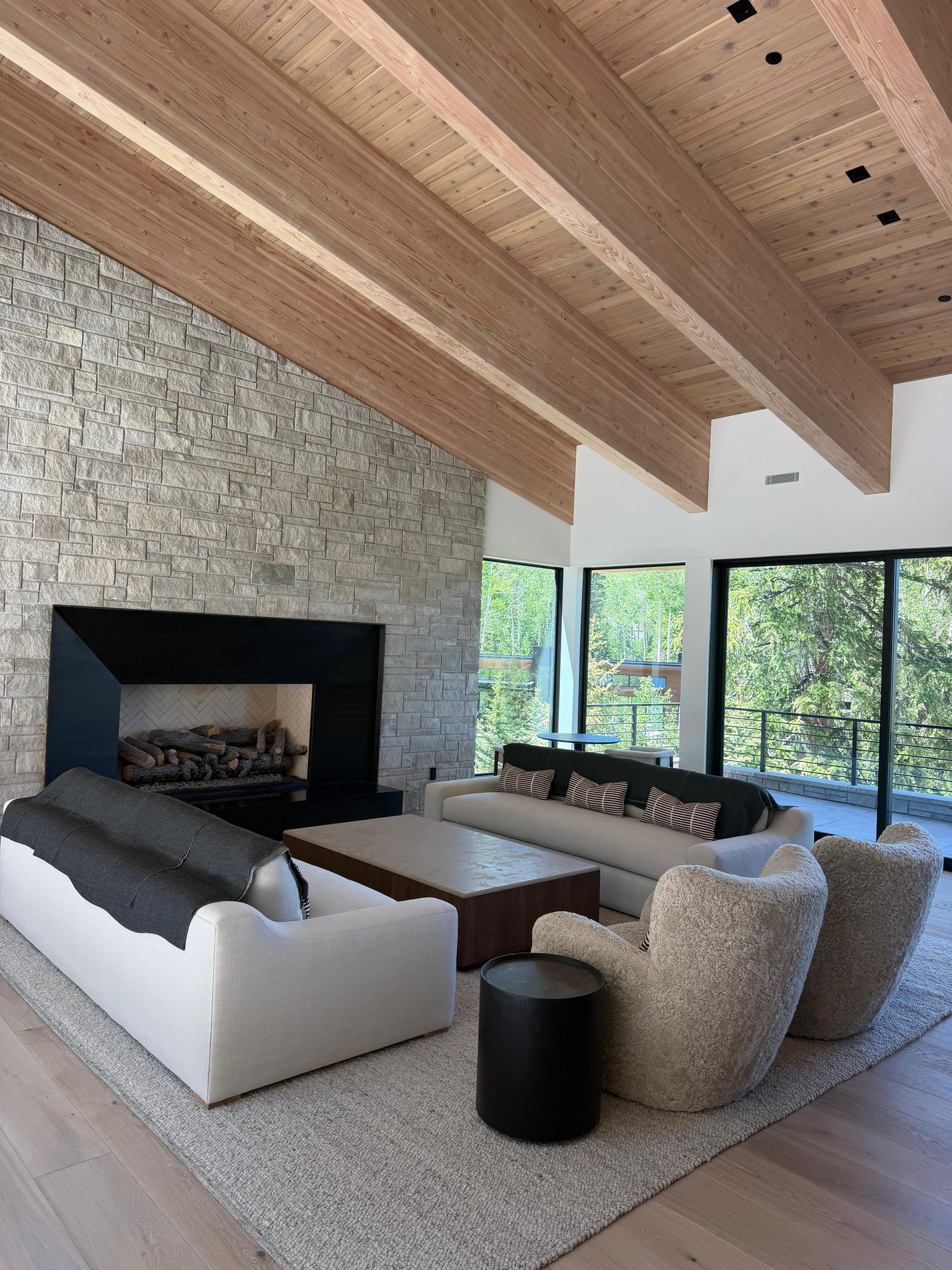 Finished fireplace lounge with stone surround, wood ceiling, and refined millwork details at The Colony