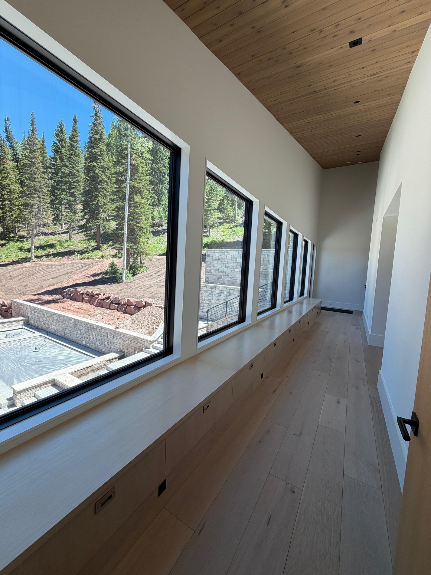 Finished window jamb corridor with long interior sill, cedar ceiling, and precise carpentry transitions